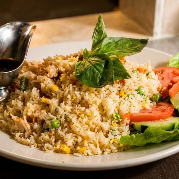 Chicken fried rice with peas, corn, basil, a side salad, and a gravy boat of sauce.